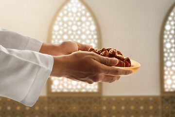 Hand of young muslim man giving dates fruit in the mosque, eid adha mubarak concept