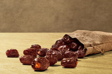 Dried dates fruits in burlap sack on wooden table