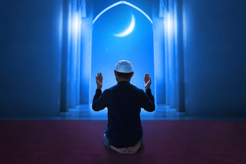 Back view of young asian muslim man praying in the mosque, eid adha mubarak concept