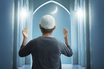 Back view of young asian muslim man praying in the mosque, eid adha mubarak concept