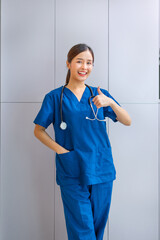 woman in a blue scrubs shirt is giving a thumbs up