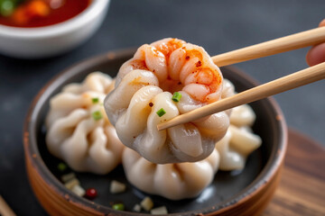 Steamed Shrimp Shumai Dumpling held with Chopsticks on Black Background