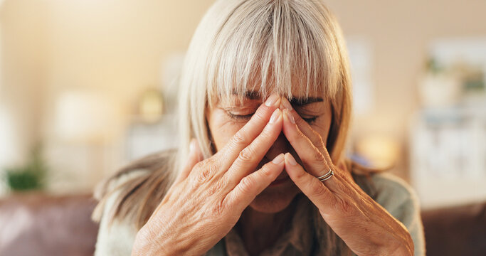 Anxiety, headache or psychology with senior woman on sofa in living room of home for mental health. Burnout, grief or pain and elderly person with depression in apartment for reaction to trauma