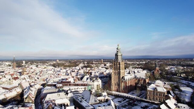 Medieval Hanseatic Dutch tower town Zutphen in the Netherlands covered in snow with historic heritage buildings and river IJssel passing by in the background behind Walburgiskerk church tower