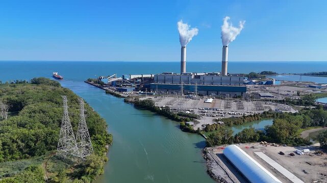 Monroe Power plant, Monroe Michigan, USA next to River Raisin in aerial approaching view, Monroe power generation plant discharging steam into the air on Lake Erie