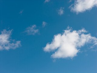Fototapeta premium Clear blue sky dotted with feathery white clouds, a serene, expansive natural background conveying calm, freedom and bright daylight for versatile design use