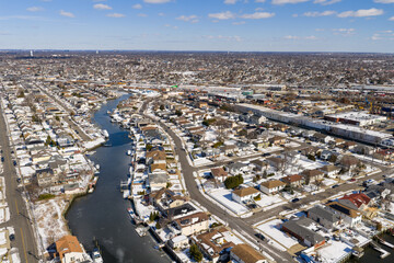 Fototapeta premium Oceanside, new york residential area featuring winding canals and homes with docks, showcasing the snowy suburban landscape during a clear winter day in nassau county