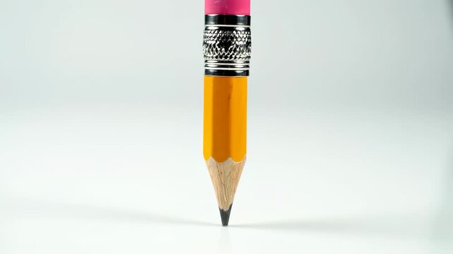 Rotating yellow pencil with pink eraser against white background in full focus
