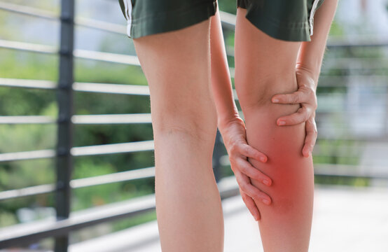 Close up of woman standing and massaging her painful calf with red highlight. Leg cramp, muscle strain, deep vein thrombosis and sport injury concept for health care and physical therapy.