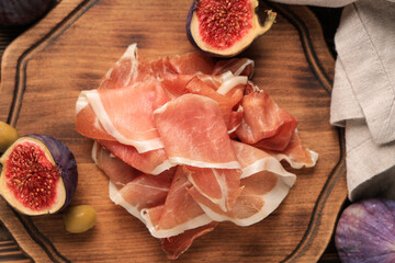 Delicious prosciutto slices, olives with fresh fig on wooden board, closeup