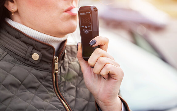 Woman Blowing Into Personal Breathalyzer Mouthpiece. Driver Testing For Alcohol Intoxication. Copy space for text