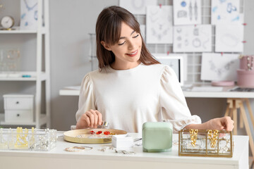 Young female jewelry designer working at table in workshop