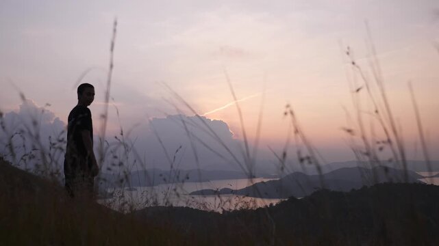 Silhouette of Person on Grass Field Hill Looking Over Water at Sunset at Mount Tapyas