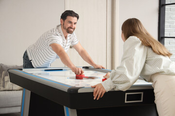 Obraz premium Young man with his girlfriend playing air hockey at home
