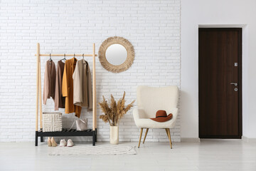 Interior of hallway with armchair, mirror and rack with stylish clothes