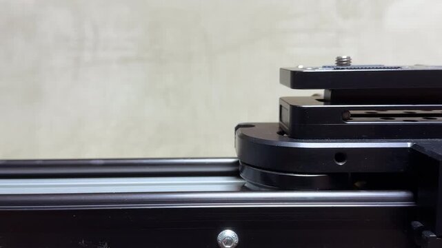 The motorized camera carriage glides smoothly along the metal rails of the slider. This precise mechanical movement results in a thin, steady whirring sound from the small electric engine.