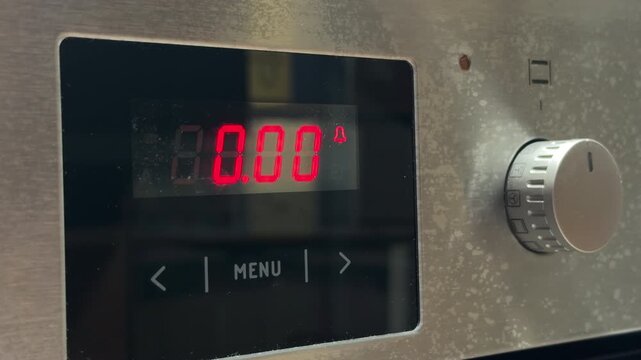 An electronic oven timer displays red digits while reaching zero. This countdown action triggers a series of short, high-pitched electronic beeps to alert the user.