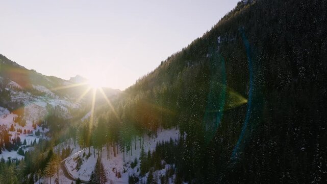 Sunlight Breaks Over Snow-covered Forests in Arabba, Nestled in the Dolomites, Italy - Aerial Drone Shot