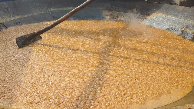 making jaggery plate, jaggery maker making gaggery , gurr making in India and (feb-08-2026) Pakistan, stirs hot and thick sugarcane juice at Jaggery production unit, Making Gur (Jaggery) from Sugarcan