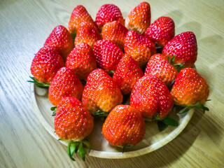 Fresh red strawberries on a wooden tray on the table.