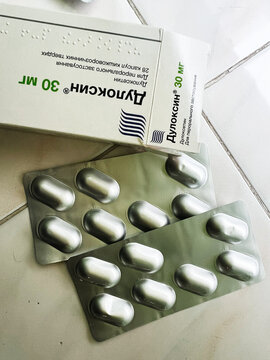 Medicine box and blister packs of Duloxin Duloxetine tranquilizer pills on a light tiled surface for pharmaceutical photography