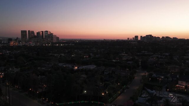 Aerial low tilting-up shot of Century City and West Los Angeles from Beverly Hills at twilight in Southern California. 4K