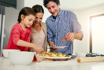 Help, parents and child with cooking pizza in home for meal prep, homemade lunch or teaching recipe. Food, people and support kid with toppings in kitchen for Italian dish, family bonding or learning