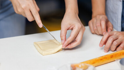Closeup hand of woman bakers chef shaping folding puff pastry dough pie on white table process...
