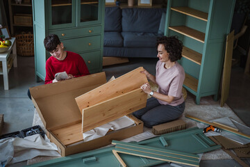 Mother and son assembling flat-pack furniture together at home