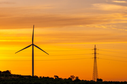 Sunset silhouette of wind turbine against sky with powerline electricity in the Terra Alta region of Catalonia Spain for renewable energy