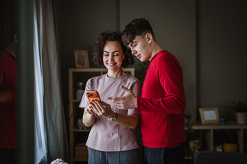 Mother and teenage son sharing content on smart phone