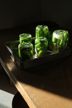 Upside down glass jars with fermenting cucumbers in natural light