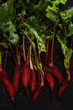 Fresh young organic beets sliced lengthwise with green leaves for roasting