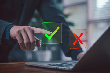 Businessman using laptop with check mark and cross icons, symbolizing decision making, approval process, evaluation, quality control, and business choice. yes or no concept, Select the check mark sign