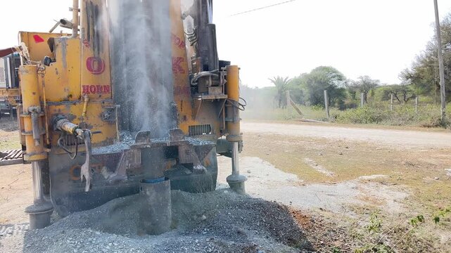 Heavy-duty industrial drilling rig machine working on a borewell with dust and debris