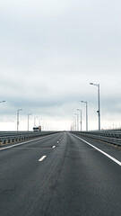 Road extends into distance with cloudy sky above and light posts lining sides