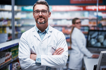 Obraz premium Medical, arms crossed and portrait of man in pharmacy for medicine, advice and healthcare. Smile, prescription and consultant with mature pharmacist in clinic for drugstore, retail and dispensary