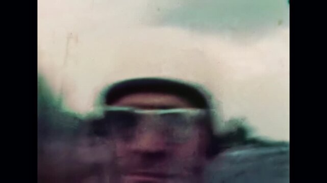 Close up, motorcyclist face riding motorcycle on road background. Biker in helmet sitting in back motorbike passenger seat, roadway moving quickly behind. Old film. Archival retro. Vintage archive