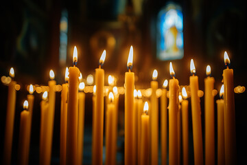 candles burning in the black background of a church	