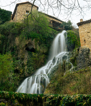 Long exposure of a beautiful waterfall flowing through the medieval village of Orbaneja del Castillo, Spain