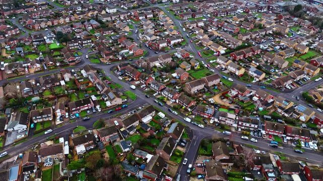 aerial panning drone shot over a suburban neighbourhood in Southampton, Hampshire named Hedge end. Shot on a quiet sunset on a cloudy winters day with many houses, fields and cars on the roads below