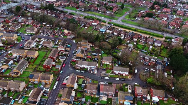 aerial panning drone shot over a suburban neighbourhood in Southampton, Hampshire named Hedge end. Shot on a quiet sunset on a cloudy winters day with many houses, fields and cars on the roads below