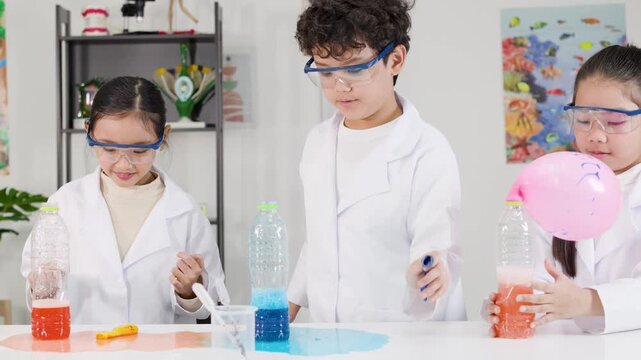 Asian Students in Lab Coats Inflating Balloons with Chemical Reactions