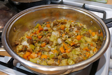 Ragout in metal pan. Vegetable stew is cooked on gas stove
