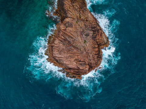 Aerial view of the rugged rock formation meeting the swirling turquoise waters, creating a mesmerizing dance of nature's raw beauty, Baie Ste Anne, Praslin, Seychelles.