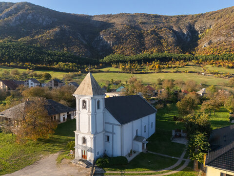 Aerial view of the Reformed Church standing proudly against the backdrop of rolling hills and verdant fields under a clear sky, Hrhov, Kosice Region, Slovakia.
