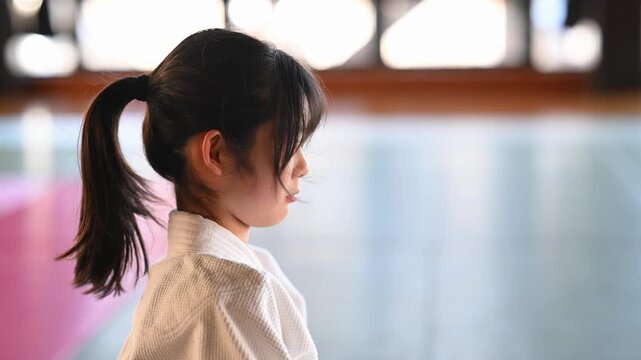 道場で気合の掛け声を出す空手着の女の子の横顔	