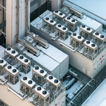 Aerial view of a snow dusted industrial rooftop bristling with ventilation units and complex ductwork, gleaming against the stark white backdrop, Duchnice, Wojew&Atilde;&sup3;dztwo mazowieckie, Poland.