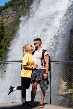Romantic young couple posing for a kiss at Steinsdalsfossen waterfall in Norway during a summer mountain hiking trip and vacation