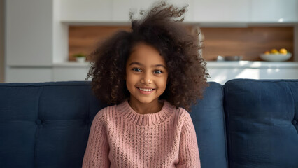 A young girl with a warm, light brown complexion and a full head of soft, voluminous curly hair sits comfortably on a plush